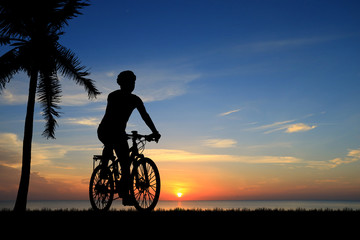 Fototapeta premium Silhouette man and bike relaxing on blurry sunrise sky background.
