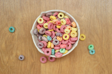 multicolored cereals in a white bowl on wood background