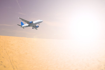 Fototapeta na wymiar Airliner over the desert in the sky. White sun shining.