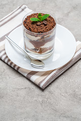 Classic tiramisu dessert in a glass on concrete background