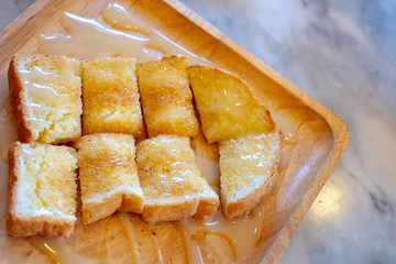 Toasted bread with butter and condensed milk in wooden dish