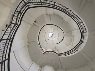 Fototapeta premium Spiral Staircase Going Up In A Lighthouse With Low Perspective and Reuleaux Triangle Shape - Looking Up At Circular Stairs
