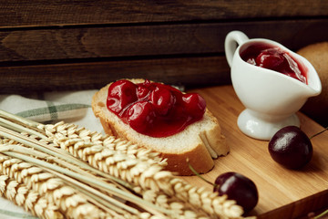 Many kind of sweet fruit, jam, and bread placing together on wooden board near window.