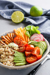 Healthy buddha bowl with chicken, quinoa and fresh vegetables.