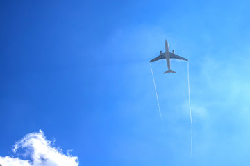 Airplan leaves a trail in the blue sky . Airliner is takking off. White cloud in the blue sky in which the plane flies.