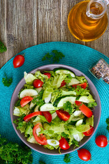 Tasty vitamin dietary salad with fresh cucumbers, tomatoes, greens. Salad from organic vegetables. Top view, flat lay.