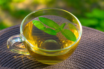  A cup of mint tea with mint leaves on the table. © Olivka888