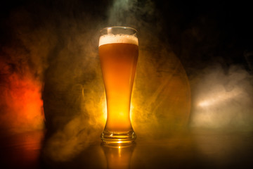 Creative concept. Beer glasses on wooden table at dark toned foggy background.