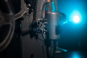 Old vintage movie projector on a dark background with fog and light. Concept of film-making.