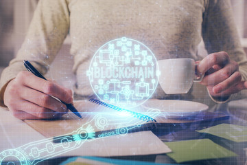 Cryptocurrency hologram over woman's hands writing background. Concept of blockchain. Multi exposure