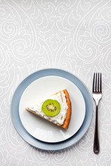Homemade cottage cheese cake with kiwi fruit and cream on a plate