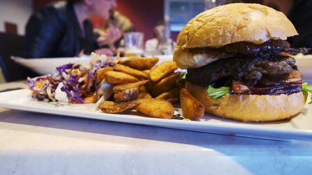Slow motion panning indoor shot of a served delicious burger