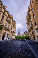 View of the Eiffel Tower between old tenements in a narrow Street