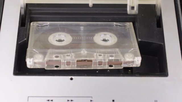 Retro technology. A person inserts an audio cassette into a tape recorder and plays it. Close-up