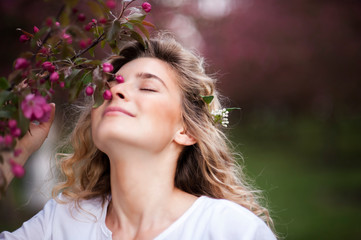 Fototapeta premium portraits of a very beautiful girl in spring park with trees in flowers