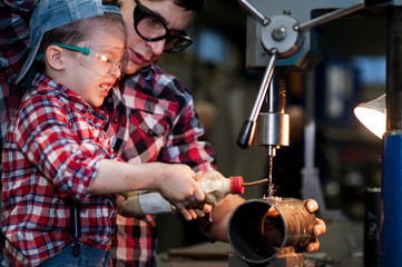 good father took his little son to work with metal. Concept of relationship, child at work turner