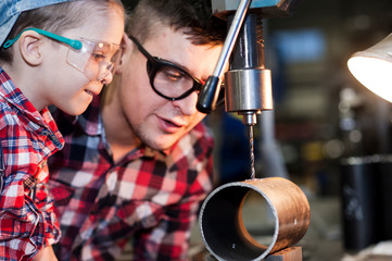 good father took his little son to work with metal. Concept of relationship, child at work turner