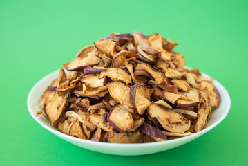 dried apples in white plate on green background
