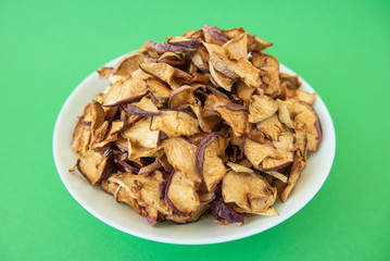 dried apples in white plate on green background