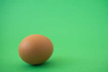 brown raw egg on green background