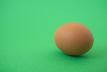 brown raw egg on green background