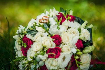 Bouquet of roses with golden wedding rings on it