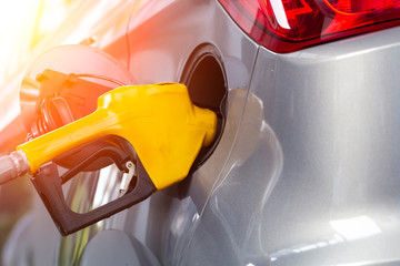 The fuel dispenser is filling the car in the gas station.