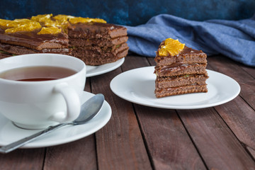 chocolate sponge cake decorated with orange slices cup of tea  on wooden table soft focus