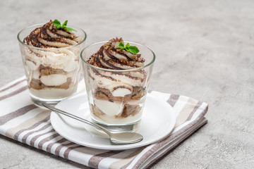 Classic tiramisu dessert in a glass on concrete background