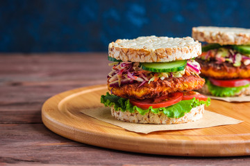 healthy snack burger with rice crackers carrot cutlet lettuce coleslaw tomato cucumber on round cutting board copy space