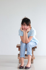 Fashion Portrait of Young  asian woman wearing natural fabric linen minimal clothing sitting on wooden chair thinking - copy space white background