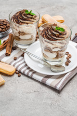 Classic tiramisu dessert in a glass on concrete background