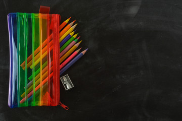 Back to school. Rainbow pencil case with school supplies for student. Black background. Copy space.