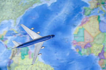 Toy plane over world map. Airplane flying through the Atlantic. Air trip, travel by plane, booking tickets, flight by aircraft concept