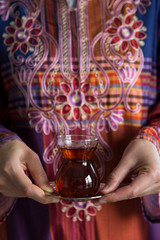 the woman wearing traditional clothes service a glass of tea for breakfast.