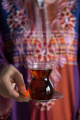 the woman wearing traditional clothes service a glass of tea for breakfast.