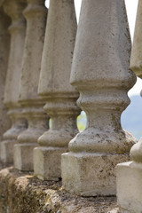 Fototapeta na wymiar Concrete balustrade with classical pillars standing in a row, protecting a garden in the tuscany. Beautiful detail of an old fence surrounding a noble property