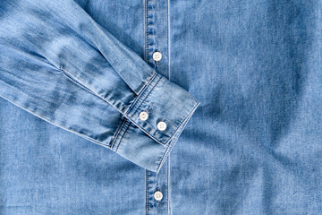 Fototapeta premium Sleeve of blue denim shirt. Clothes concept. Details of shirt on wooden background.