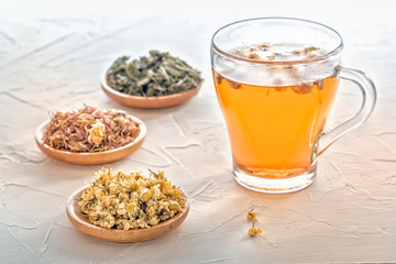 Herbal tea with pharmaceutical chamomile, dry chrysanthemum and hunters on a white table