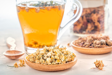 Herbal tea with pharmaceutical chamomile, dry chrysanthemum and hunters on a white table