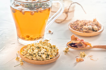 Herbal tea with pharmaceutical chamomile, dry chrysanthemum and hunters on a white table