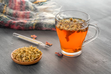 Herbal tea with pharmaceutical chamomile on a gray wooden table