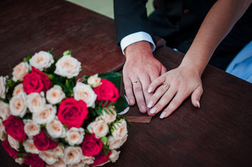 Obraz na płótnie Canvas Bride and groom hands with flower bouquet on the table