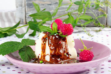 Cream pudding with chocolate sauce, raspberry and mint on  tablecloth