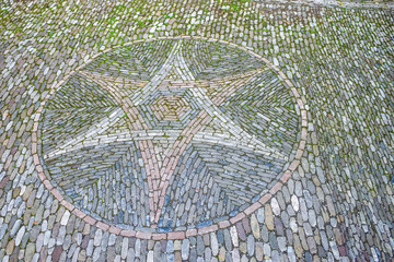 Vintage paving stone of pattern of star with moss from medieval time