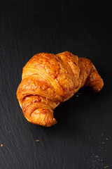 Food concept French croissant on black slate board with copy space