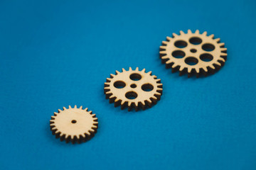 Fototapeta na wymiar Wooden gear on a blue background. Abstract background for presentations and banners. The concept of technology and industry, the think process. Part of a large complex mechanism. Banner.