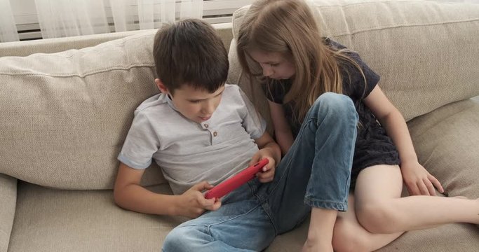 Brother and sister enjoying game together on mobile phone at home