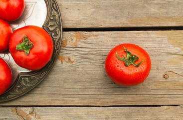 Ripe tomatoes on a wooden table in a metal plate. Close-up