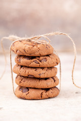Image shows a stack of american chocolate chip cookies on rustic wooden plank.